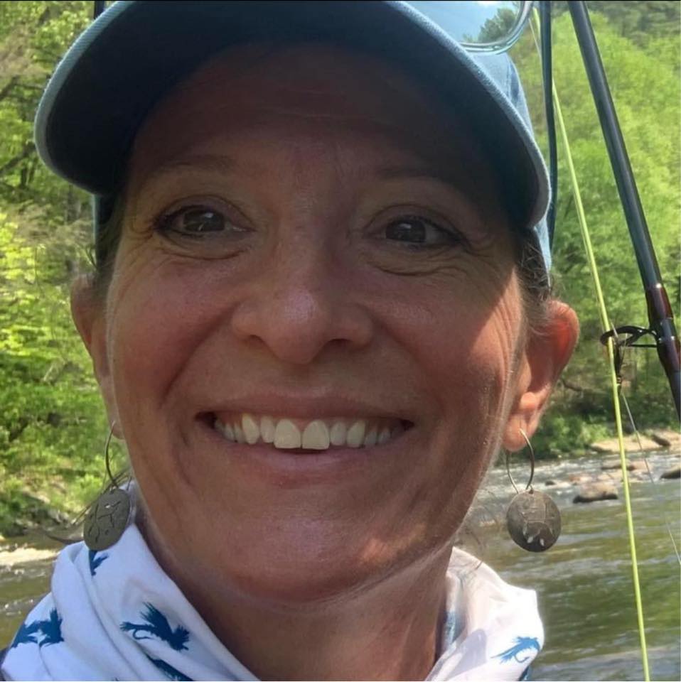 Pretty woman with a fishing pole, fishing hat and neckerchief on the water fishing.