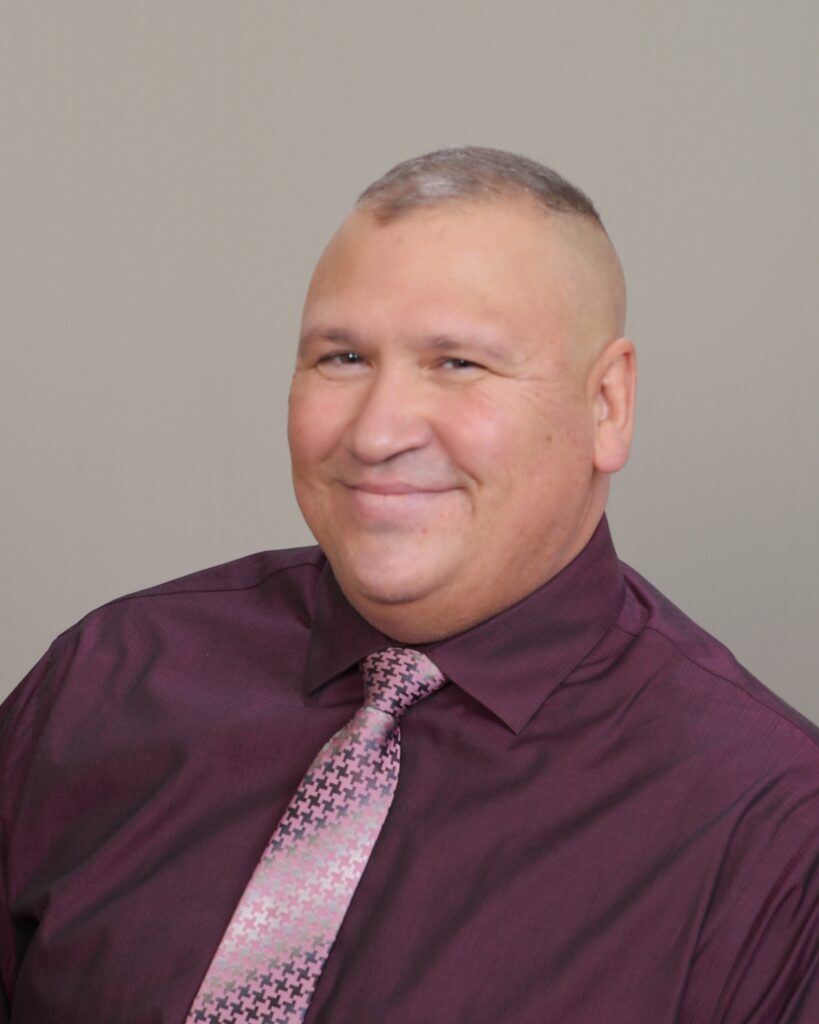 Man with crew cut in a plum shirt with pink tie